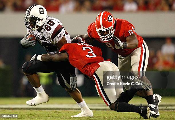 Weslye Saunders of the South Carolina Gamecocks breaks a tackle by Bryan Evans and DeAngelo Tyson of the Georgia Bulldogs at Sanford Stadium on...