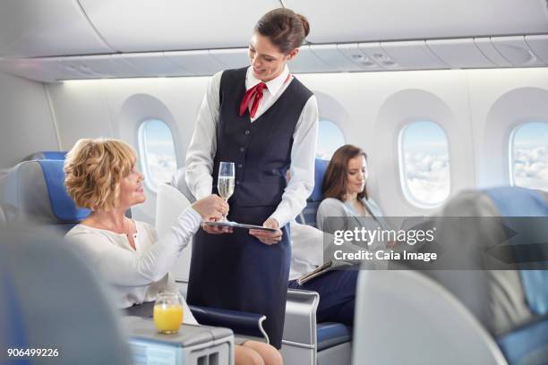 flight attendant serving champagne to woman in first class on airplane - first class champagne stock pictures, royalty-free photos & images