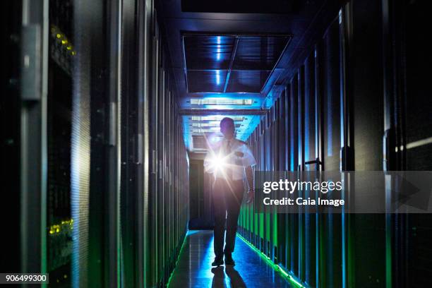 male security guard with flashlight walking in dark server room - electric torch stock pictures, royalty-free photos & images