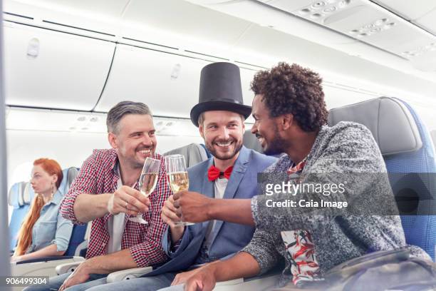 young male friends toasting champagne glasses in first class on airplane - despedida de solteiro - fotografias e filmes do acervo