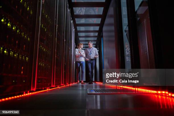 it technicians talking and walking in dark server room - mainframe stock-fotos und bilder