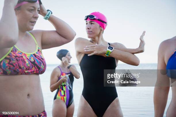 female open water swimmers with smart watch stretching and preparing - open workouts stock-fotos und bilder