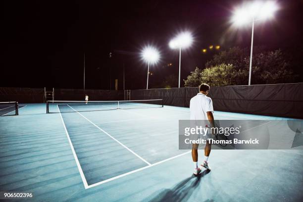tennis teammates practicing together on outdoor court at night - tennis stock-fotos und bilder