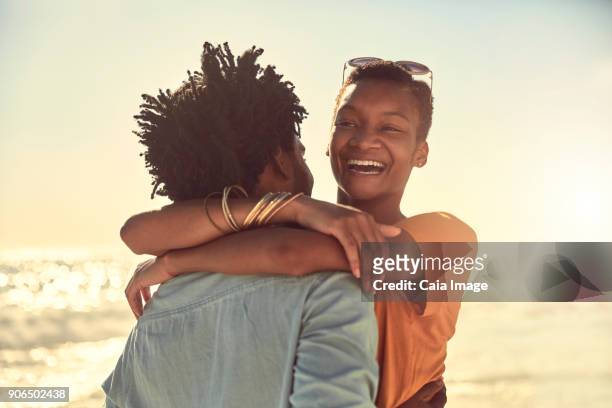 Laughing young couple hugging on sunny summer beach