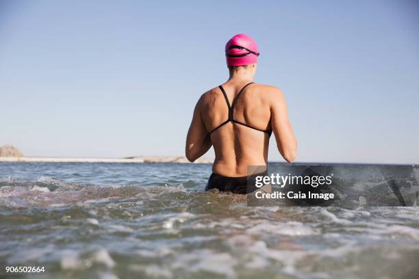 female open water swimmer wading in sunny ocean surf - waist deep in water stock pictures, royalty-free photos & images