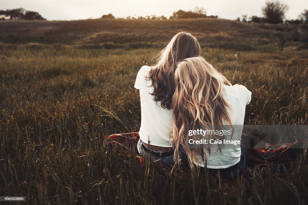 Tranquil teenage sisters in white t-shirts in rural field