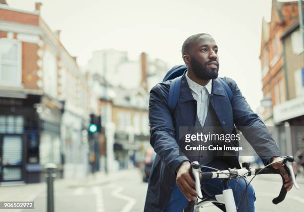african businessman commuting, riding bicycle on urban street - london bikes stock pictures, royalty-free photos & images