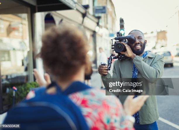 young man with video camera videoing woman on street - tv reporter street stock pictures, royalty-free photos & images