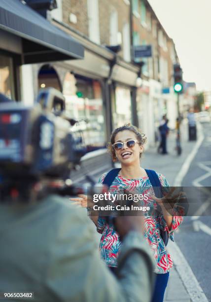 enthusiastic young woman posing for video camera on urban street - tv reporter street stock pictures, royalty-free photos & images