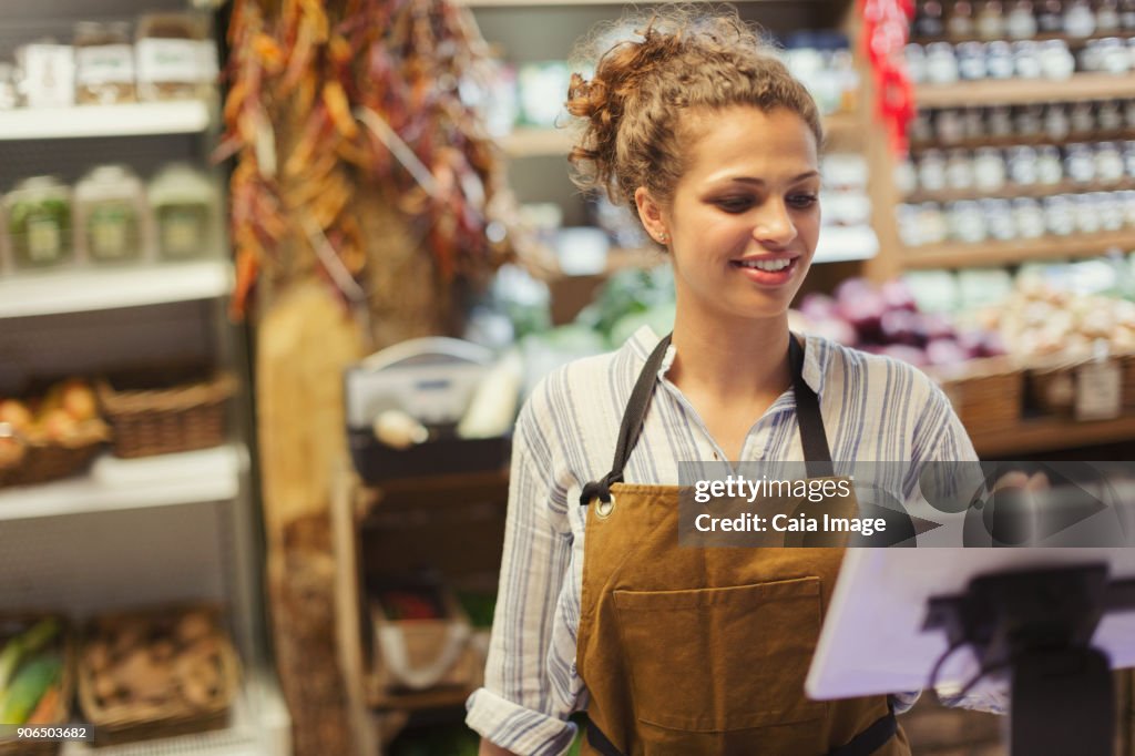 Female cashier using touch screen cash register in grocery store