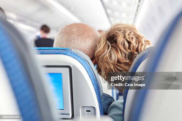 rear view affectionate mature couple leaning on airplane - vliegtuigstoel stockfoto's en -beelden