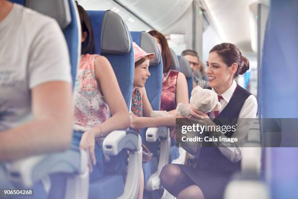 girl showing teddy bear to female flight attendant on airplane - air stewardess stock pictures, royalty-free photos & images