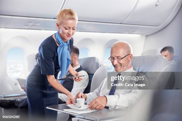 flight attendant serving espresso coffee to businessman in first class on airplane - hostess foto e immagini stock