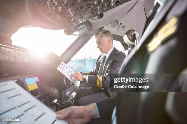 male pilots with clipboard preparing in airplane cockpit - flight-instruments stockfoto's en -beelden