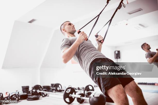 jonge atleet mannen doen achteroefening met schorsing riemen in sportschool - suspension training stockfoto's en -beelden