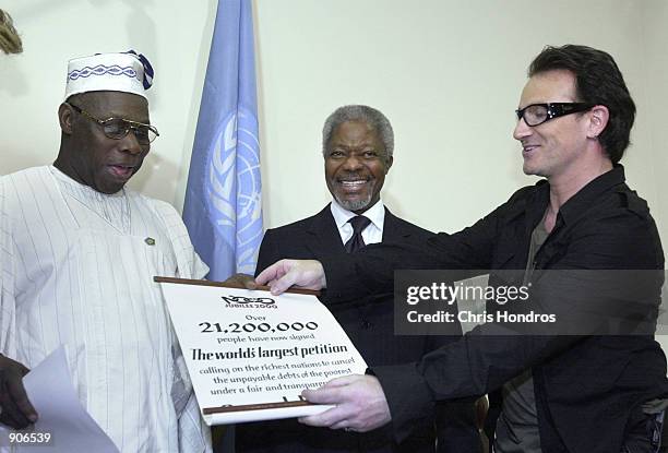 Nigerian President Olusegun Obasanjo, left, United Nations Secretary-General Kofi Annan, center, and Bono, from the rock group U2, display a banner...