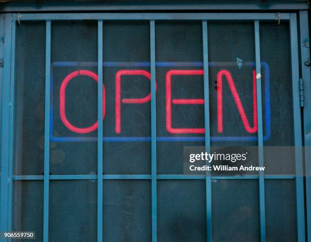 neon "open" sign behind security bars - irony stock pictures, royalty-free photos & images