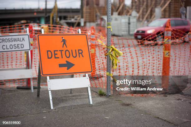 detour sign on city sidewalk outside a construction site - detour stock-fotos und bilder