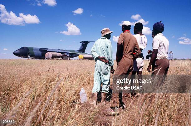 Namibian workers watch operations following the landing of a Military Airlift Command C-5B Galaxy aircraft at Grootfontein Logistics Base. The Galaxy...