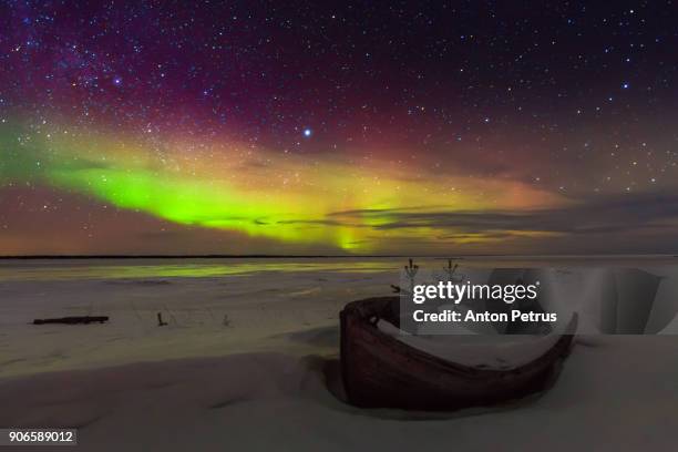 northern lights on the lake shore with an old boat - northern mariana islands stock-fotos und bilder