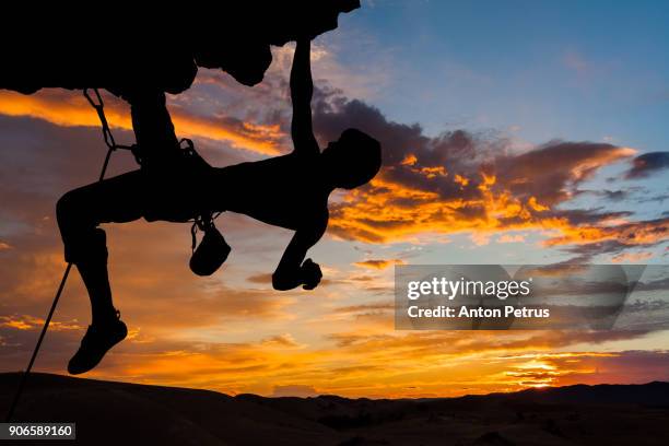 silhouette of rock climber on cliff at sunset - rock overhang foto e immagini stock