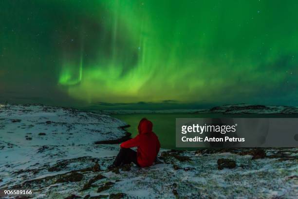 man in a red jacket on a background of the northern lights - red coat stock pictures, royalty-free photos & images