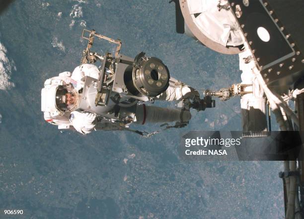 Astronaut Tamara Jernigan, backdropped against the earth , totes part of a Russian-built crane, called Strela May 30, 1999. Jernigan's feet are...