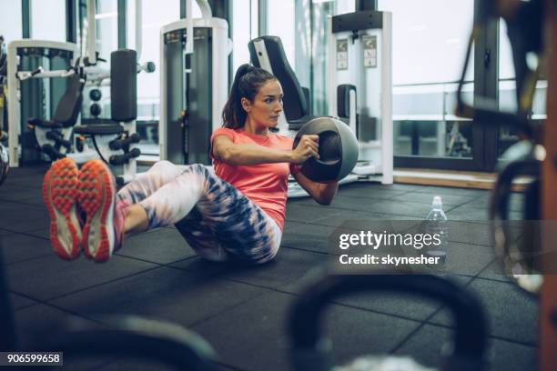 athletic woman exercising sit-ups with medicine ball in a health club. - medicine ball stock pictures, royalty-free photos & images