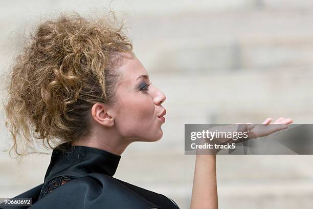 side view of a pretty female model blowing a kiss - blowing a kiss stock pictures, royalty-free photos & images