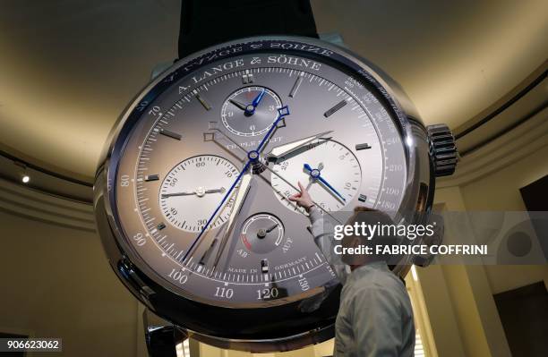 Staff gestures next to a giant watch at the stand of German watchmaker A. Lange & Soehne, owned by the Richemont group, during the 28th International...