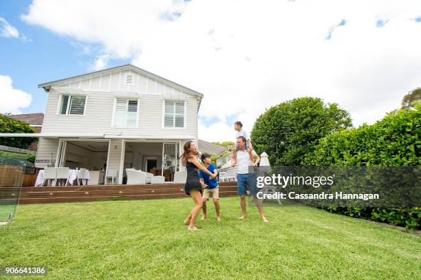 a multi-cultural family plays together in their backyard in australia - family with two children stock pictures, royalty-free photos & images