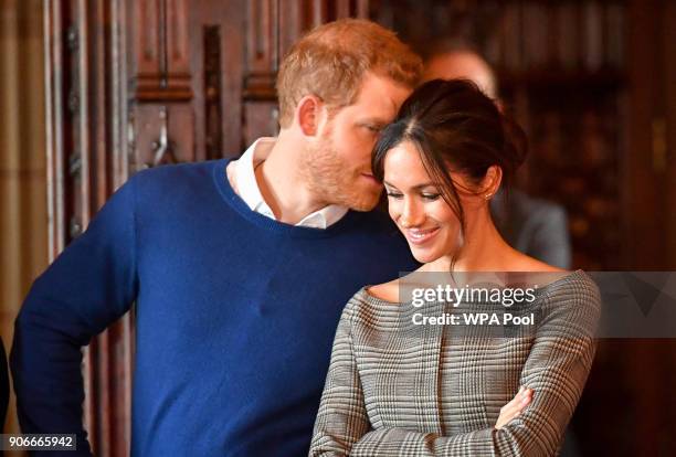 Prince Harry whispers to Meghan Markle as they watch a performance by a Welsh choir in the banqueting hall during a visit to Cardiff Castle on...