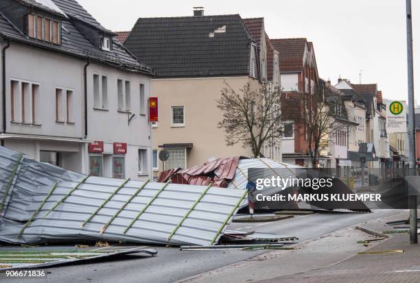 Picture taken on January 18, 2018 shows metal roofing sheets from a supermarket blocking a road in Menden, western Germany, as the region is hit by...