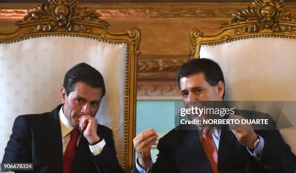 Paraguayan President Horacio Cartes speaks with his Mexican counterpart Enrique Pena Nieto during a ceremony at the presidential palace in Asuncion...