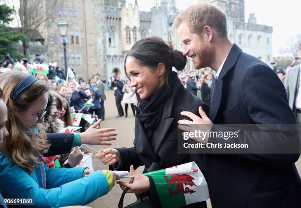 Meghan Markle writes a note for 10 year old Caitlin Clarke from Marlborough Primary School as Prince Harry looks on during a walkabout at Cardiff...