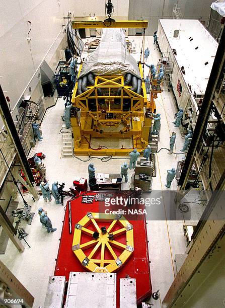 In the Vertical Processing Facility , workers check the placement of the Chandra X-ray Observatory on the stand on the floor. The stand will be used...