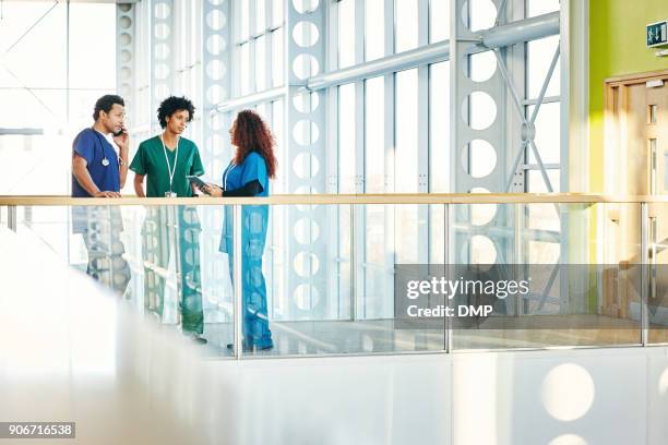 medical professionals talking in modern hospital corridor - hospital corridor stock pictures, royalty-free photos & images