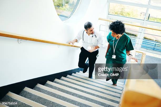 two doctors on staircase having conversation - staircase stock pictures, royalty-free photos & images