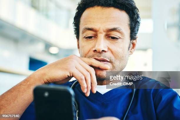 doctor reading text message on his mobile phone - doctor reading stock pictures, royalty-free photos & images