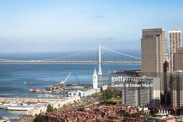 an aerial view of san francisco embarcadero with the iconic ferry terminal building, right next to the financial district, and the san francisco oakland bay bridge - embarcadero summer photos et images de collection