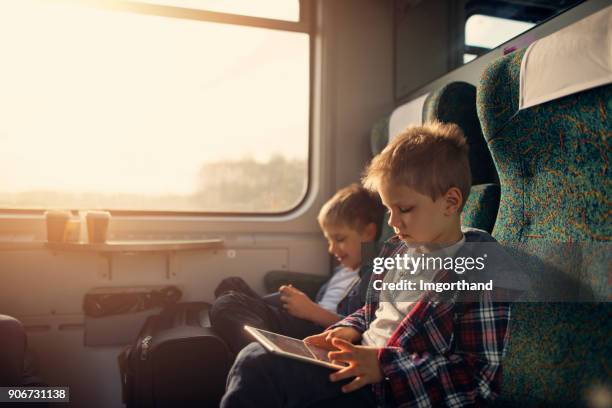 kleine jungs spielen mit digitalen tabletten in zug - familie in der bahn stock-fotos und bilder