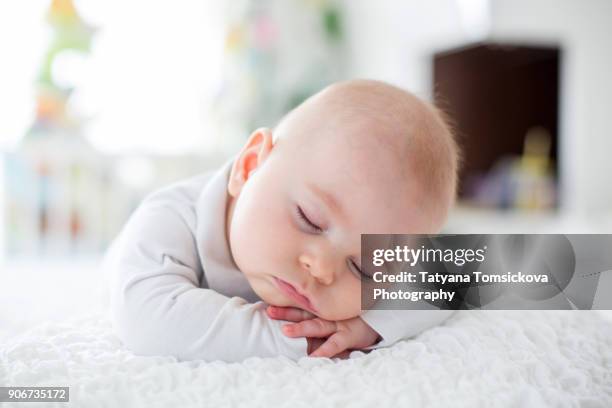 beautiful baby boy in white knitted cloths and hat, sleeping sweetly posed in bed - boy asleep in bed bildbanksfoton och bilder