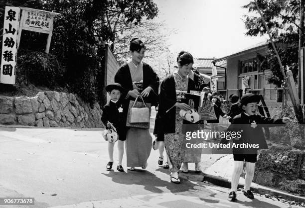 Children hand in hand with their mothers in Japan, 1960s.