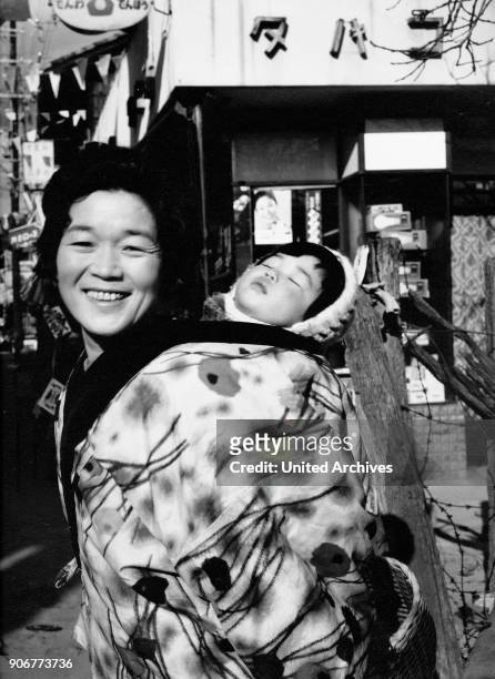Mother carrying her baby through the streets of Kyoto, Japan 1960s.