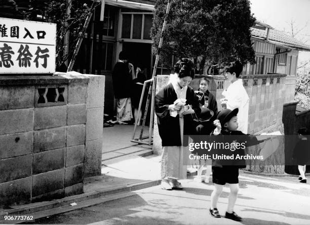 Children and mothers hand in hand at children's first day at school, Japan 1960s.