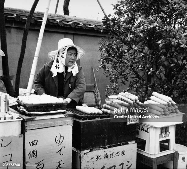 Woman selling toasted corn cobs on the street, Japan 1960s.