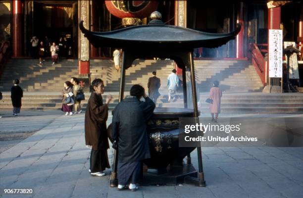 Two women at a pot with holy smoke at Asakusa Kannon temple at Tokyo, Japan 1960s.