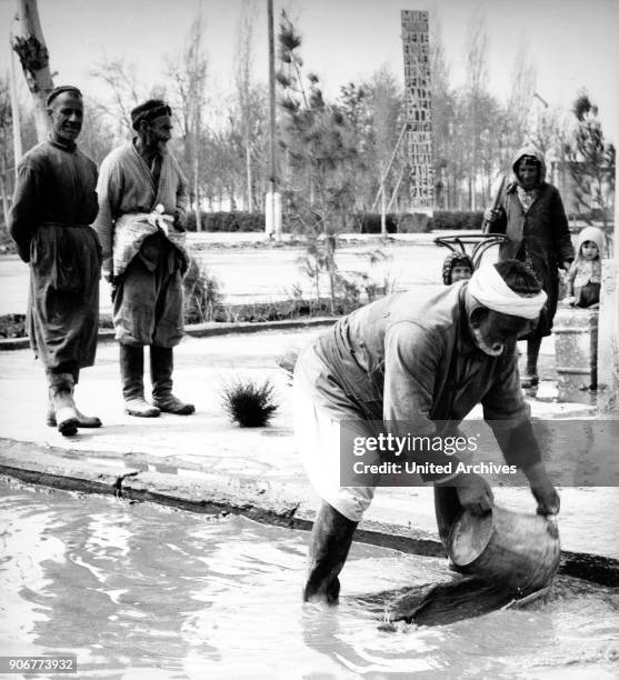 Man scooping water after a downpour at Bukhara in Uzbekistan, Soviet Union, 1970s.