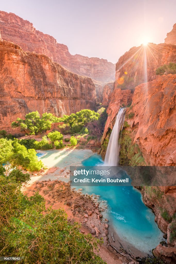 Havasu Falls in Arizona plunges in turquoise waters as the sun rises above the cliffside