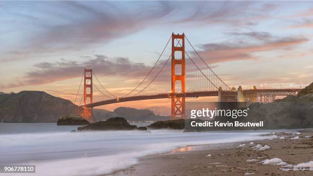 the mighty golden gate bridge as seen from baker beach at sunset - baker beach stock pictures, royalty-free photos & images